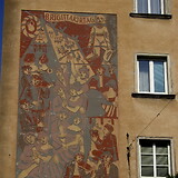 Hermine Aichenegg, Brigitta-Kirtag. Gemeindebau Friedrich-Engels-Platz 17 (Wien XX). Das Sgraffito-Wandbild (1951) basiert auf Motiven aus Franz Grillparzers Novelle Der arme Spielmann (1847).