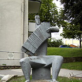 Elisabeth Turolt, Ziehharmonikaspieler, Zementplastik (1955/58). Gemeindebau ‚Ernest-Bevin-Hof‘, Andergasse 12–22 (Wien XVII)